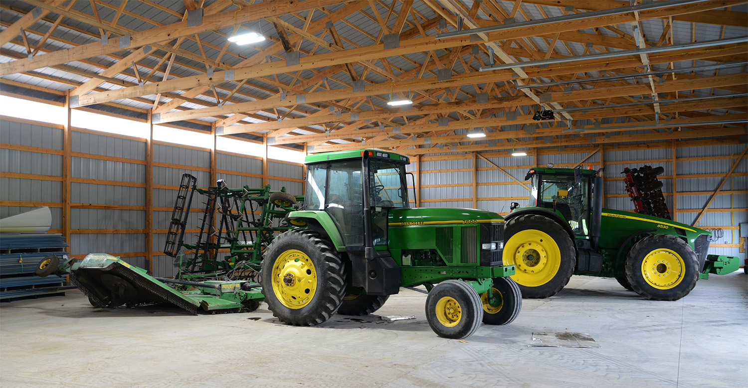 interior showing the framing of a post frame ag building with two tractors inside